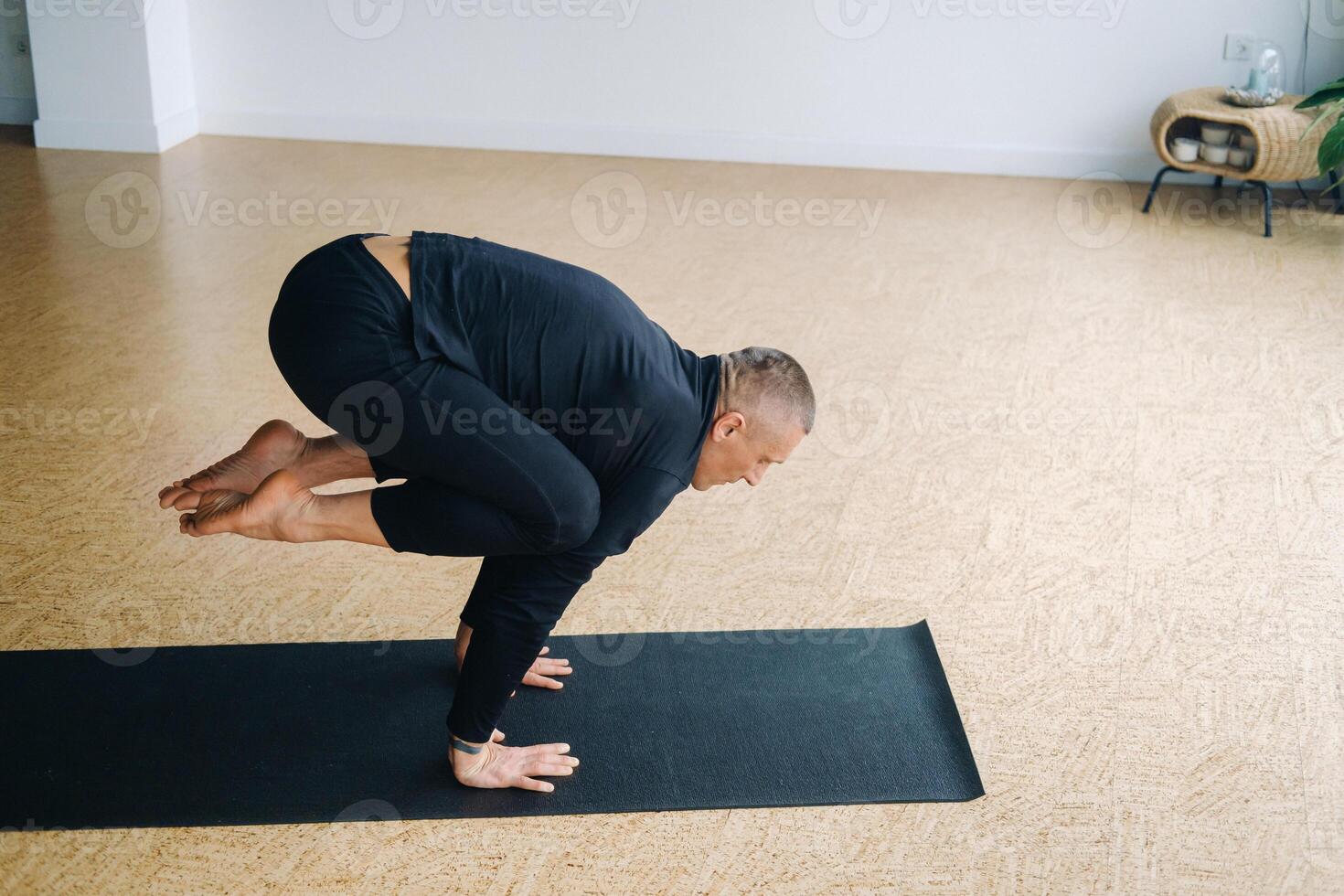 An athletically built man does yoga in the gym on a mat photo