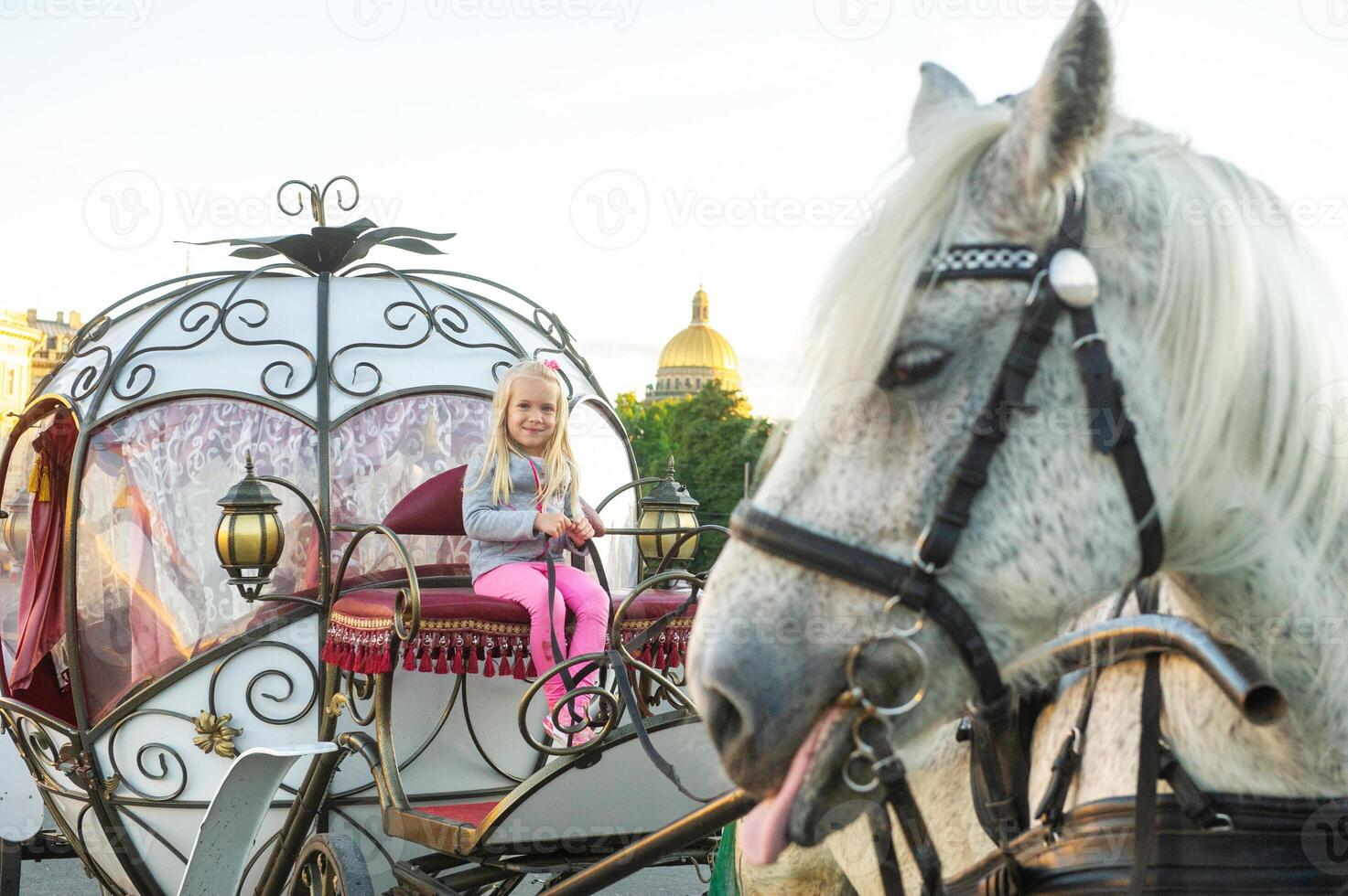 a child sits in the driver's seat in an old carriage on Palace Square in St. Petersburg photo