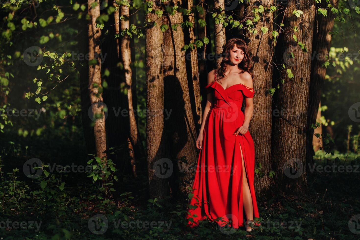Spring Portrait of a laughing girl in a long red dress with long hair walking in the Park in the woods photo