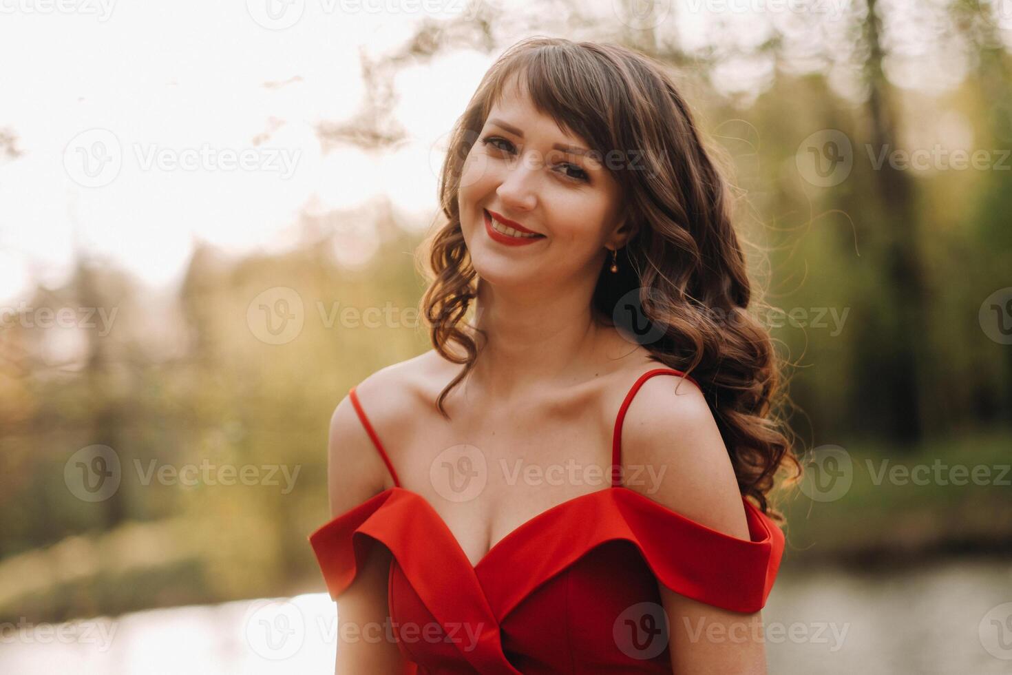 Spring Portrait of a laughing girl in a long red dress with long hair walking in the Park in the woods photo