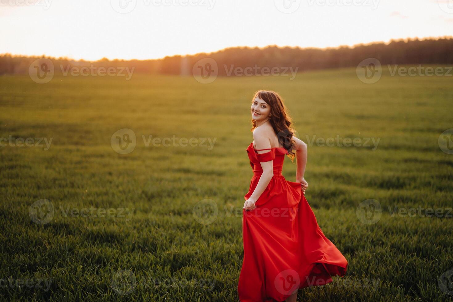 a beautiful girl in spring in a red dress is walking in a field at sunset. Taken from the air by a quadrocopter photo