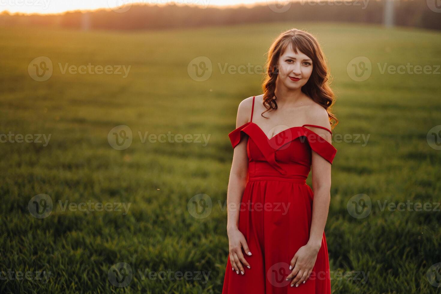 a beautiful girl in spring in a red dress is walking in a field at sunset. Taken from the air by a quadrocopter photo