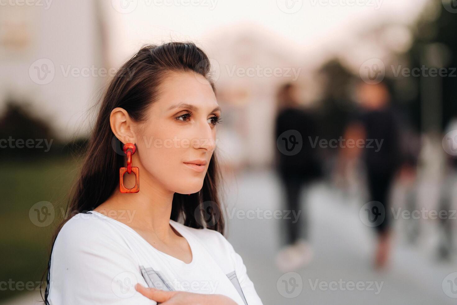 Close-up portrait of a girl with red earrings in white clothes in the city photo