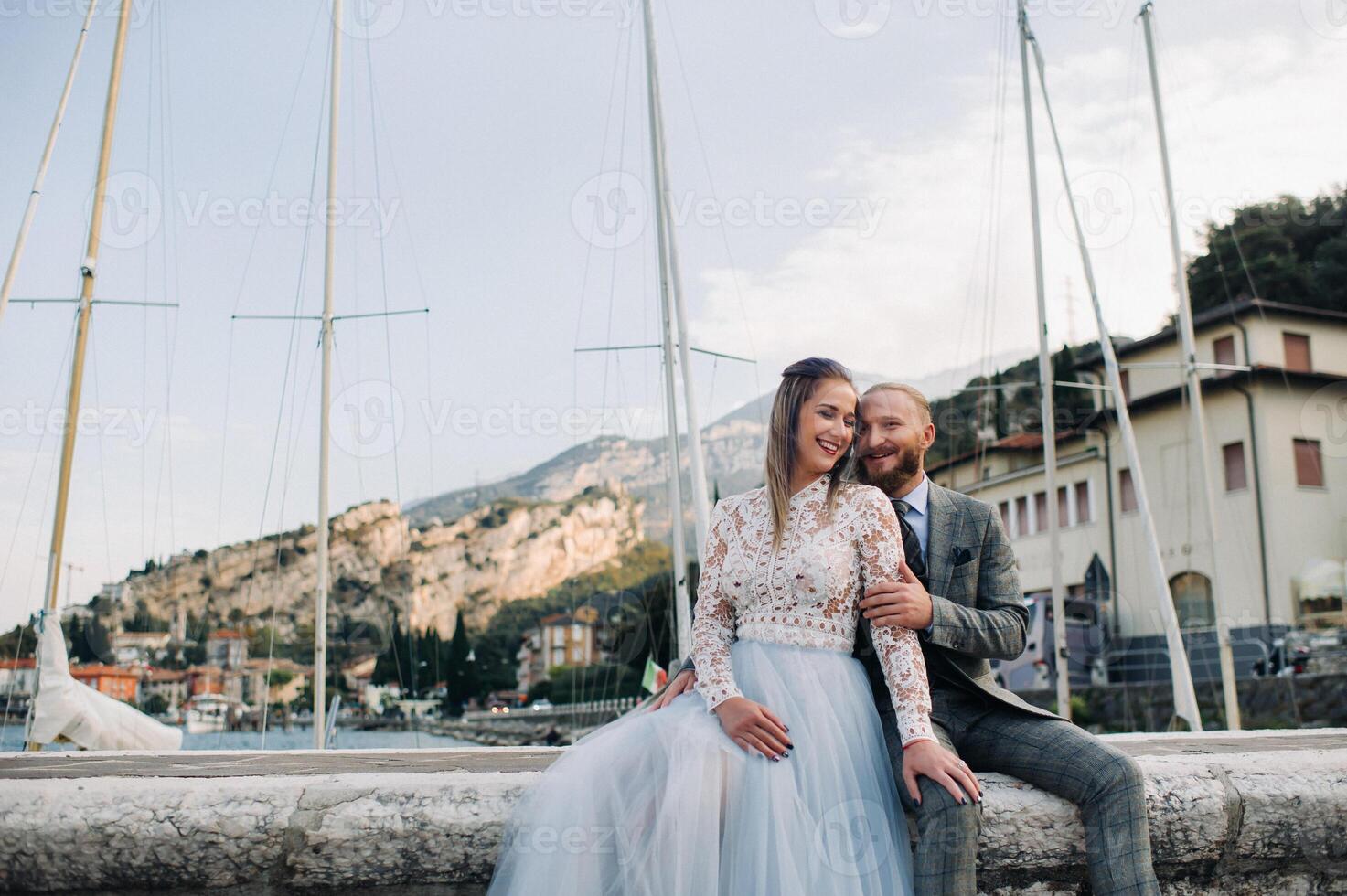 Italy, Lake Garda. A beautiful couple on the shores of lake Garda in Italy at the foot of the Alps.A man and a woman sit on a pier in Italy photo