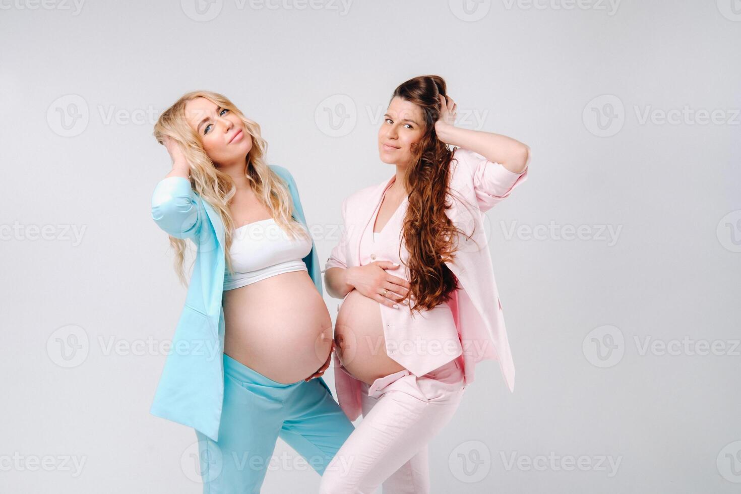 Two pregnant women with big bellies in suits on a gray background photo