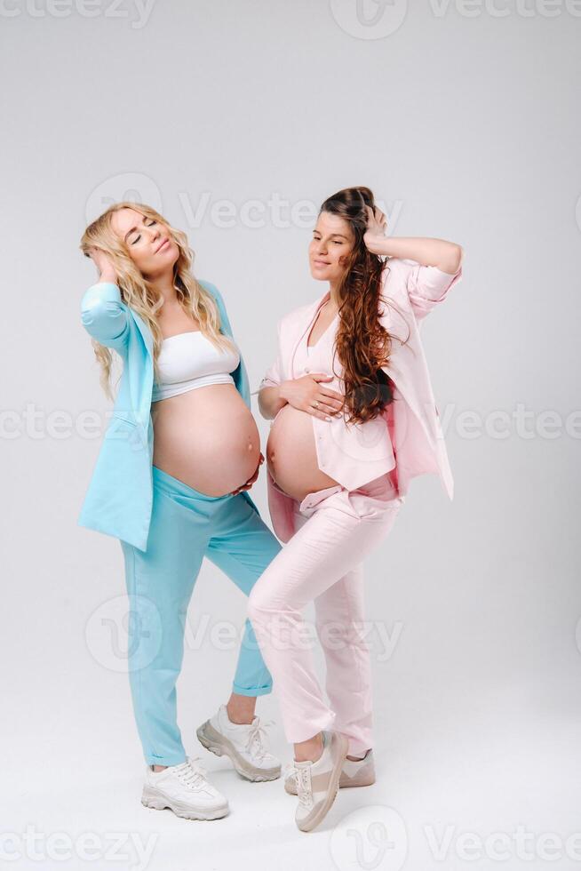 Two pregnant women with big bellies in suits on a gray background photo