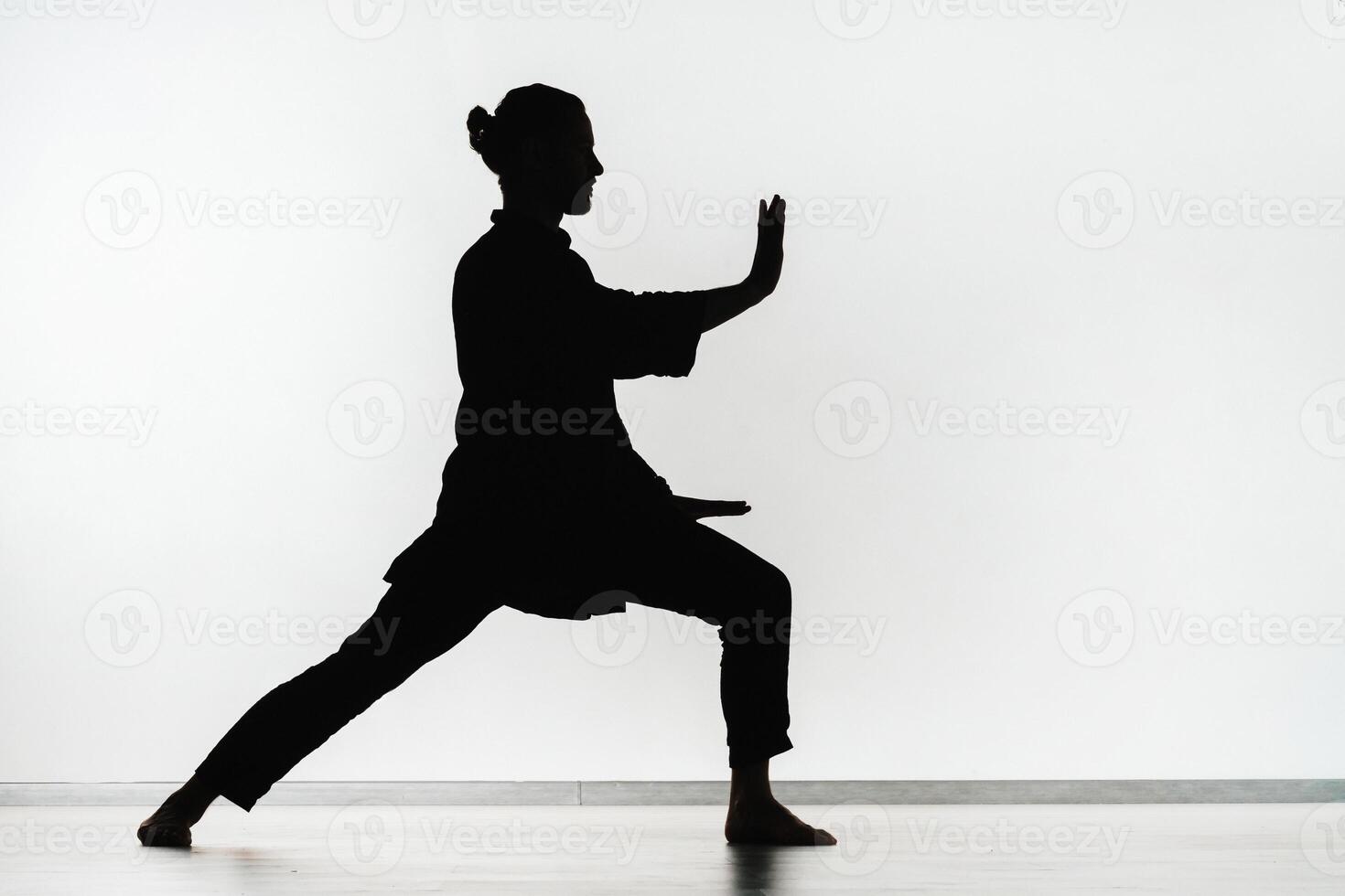Silhouette of a person practicing qigong energy exercises on a light background photo