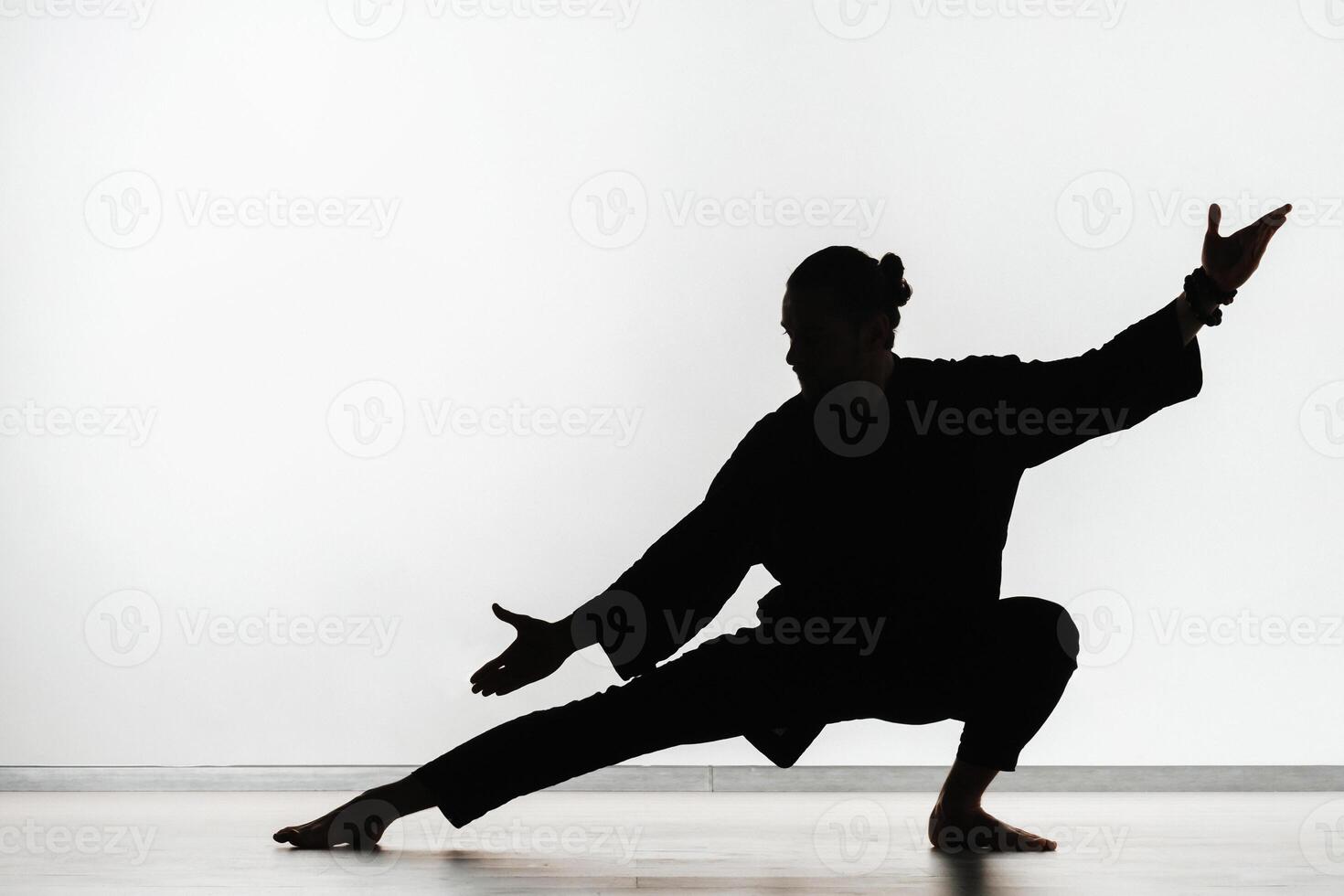 Silhouette of a person practicing qigong energy exercises on a light background photo