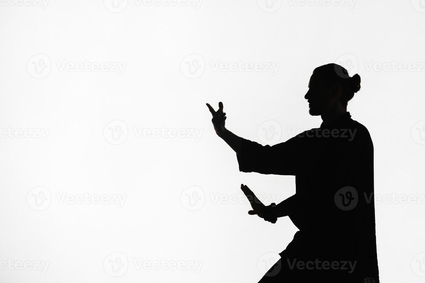 Silhouette of a person practicing qigong energy exercises on a light background photo