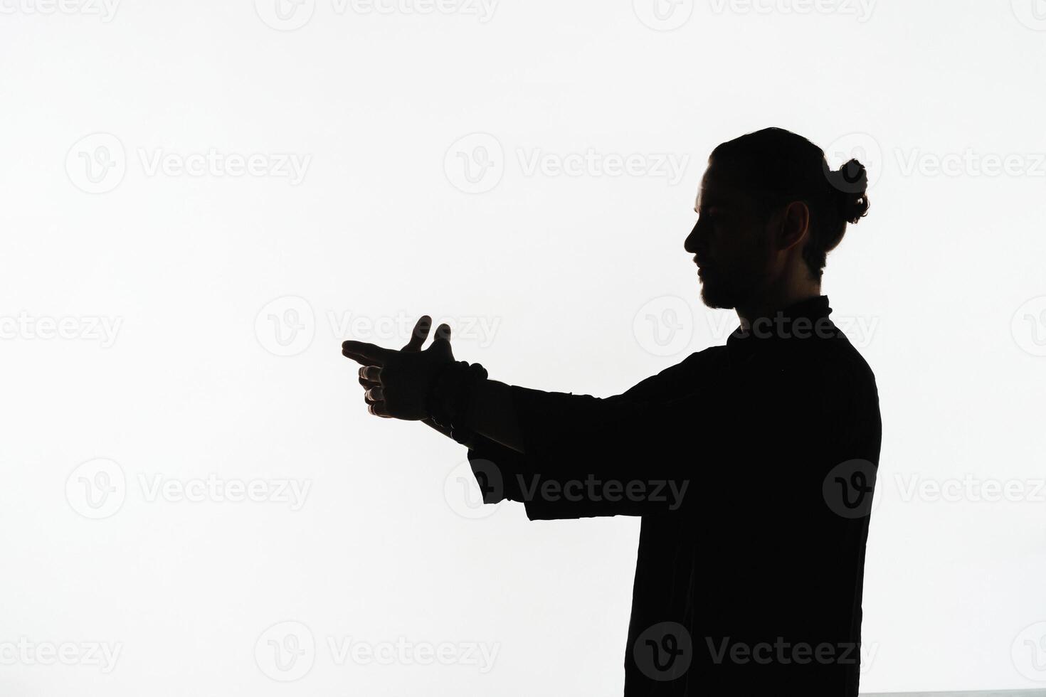 Silhouette of a person practicing qigong energy exercises on a light background photo
