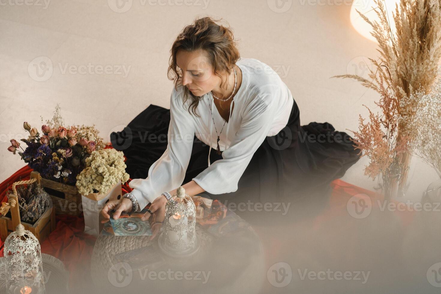 Women's circle and practice in the use of metaphorical cards. The girl is sitting surrounded by flowers photo