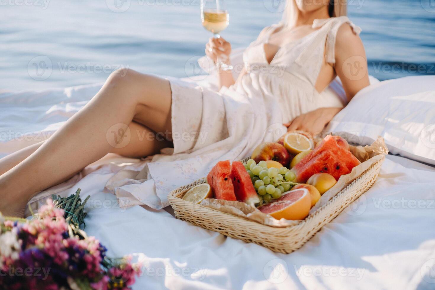 a woman in bed is resting on the seashore with a glass of champagne and fruit photo