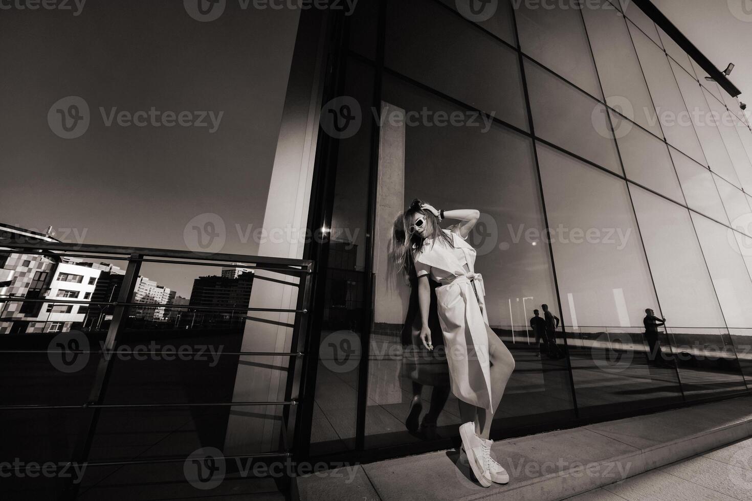 Stylish girl in glasses and a white summer coat in the city photo