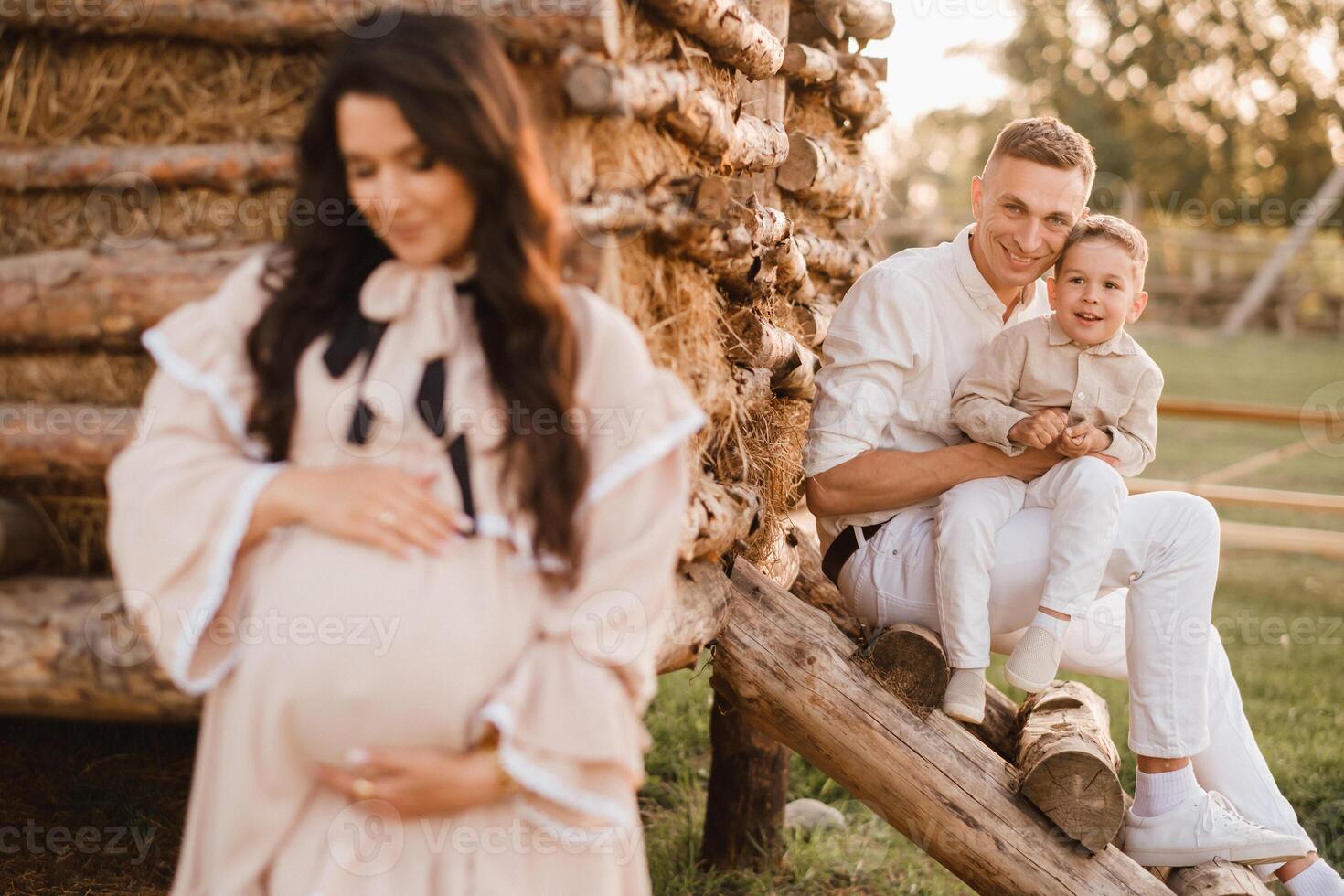 A stylish family in the countryside at sunset. A pregnant woman with her husband and son in nature photo