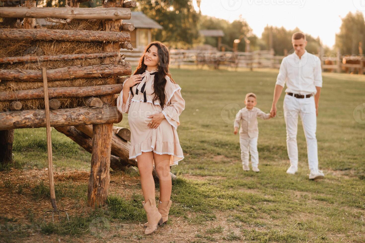 A stylish family in the countryside at sunset. A pregnant woman with her husband and son in nature photo