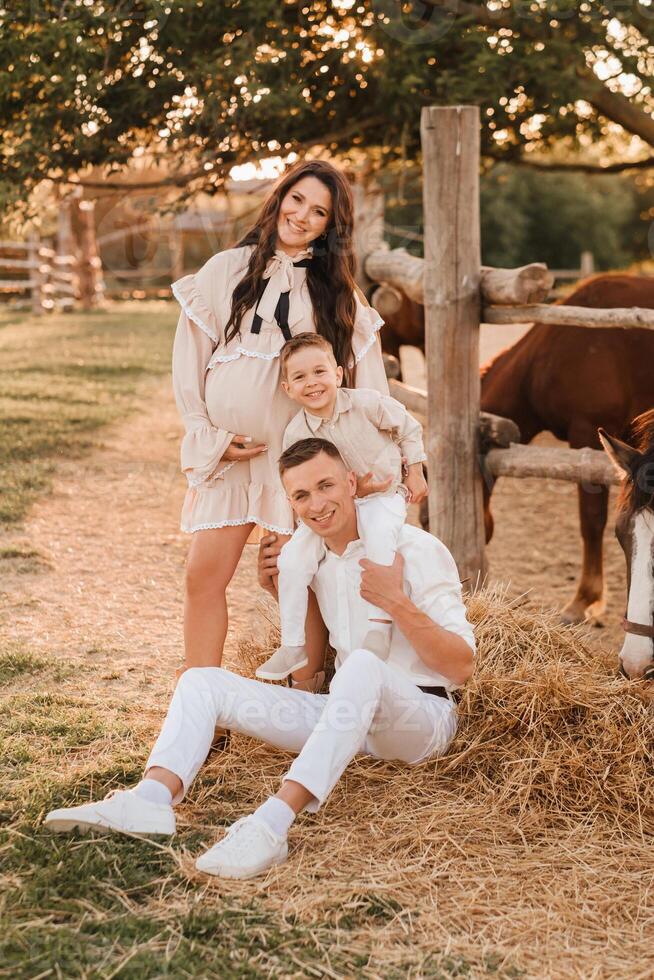 Happy family near horses at a farmer's ranch at sunset photo