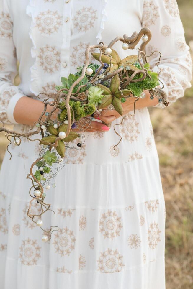 The bride holds an unusual braided wedding bouquet in her hands photo