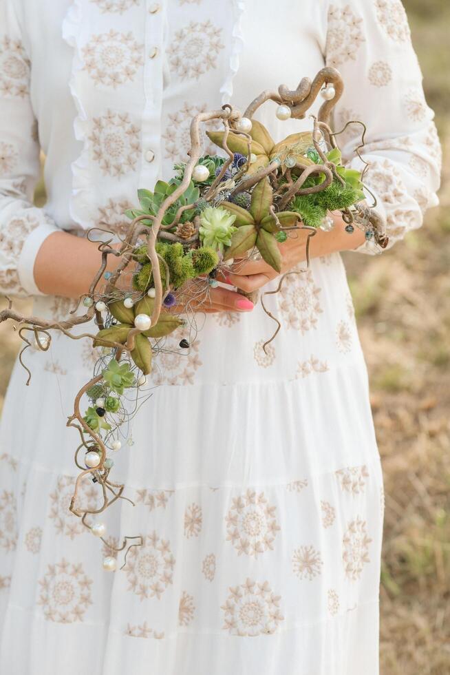The bride holds an unusual braided wedding bouquet in her hands photo