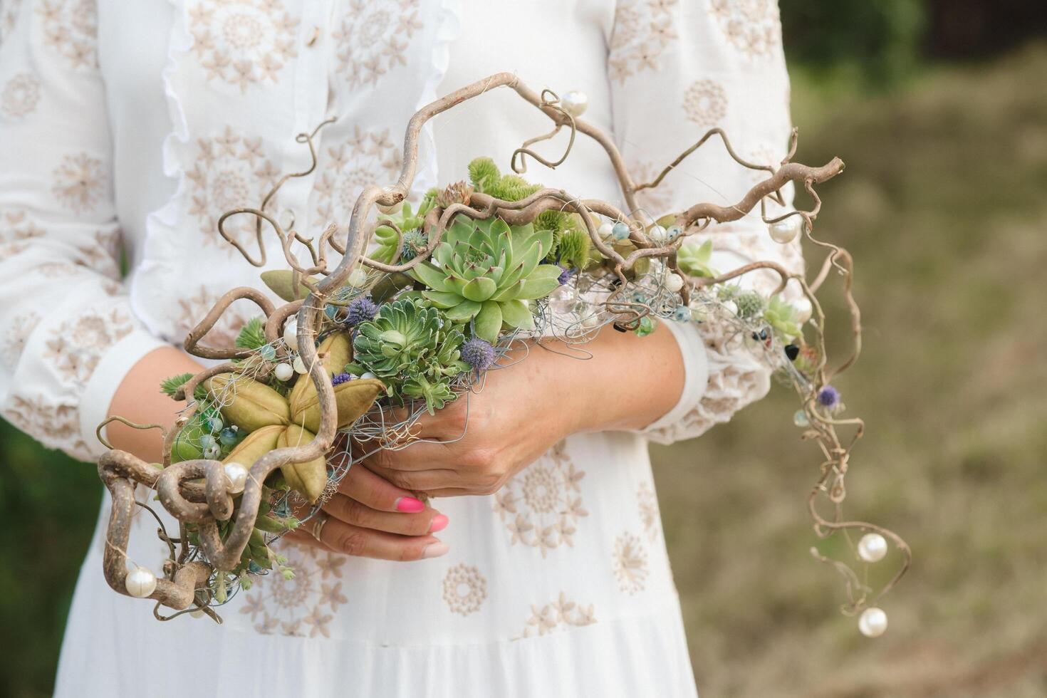 The bride holds an unusual braided wedding bouquet in her hands photo