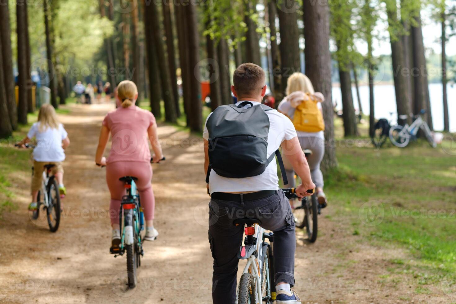 A group of cyclists with backpacks ride bicycles on a forest road enjoying nature photo