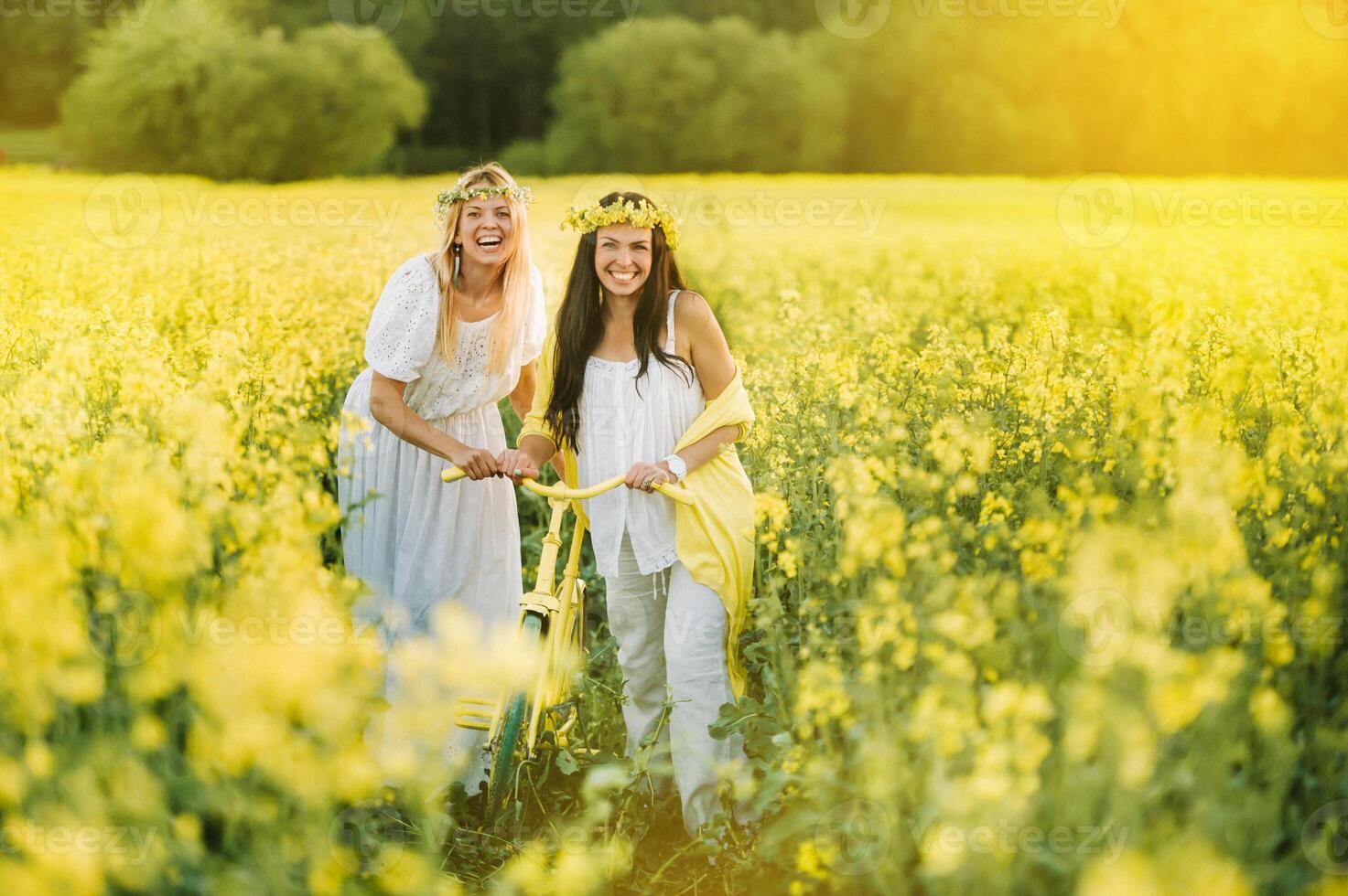 two women in a rapeseed field with a bicycle enjoy a walk in nature rejoicing photo