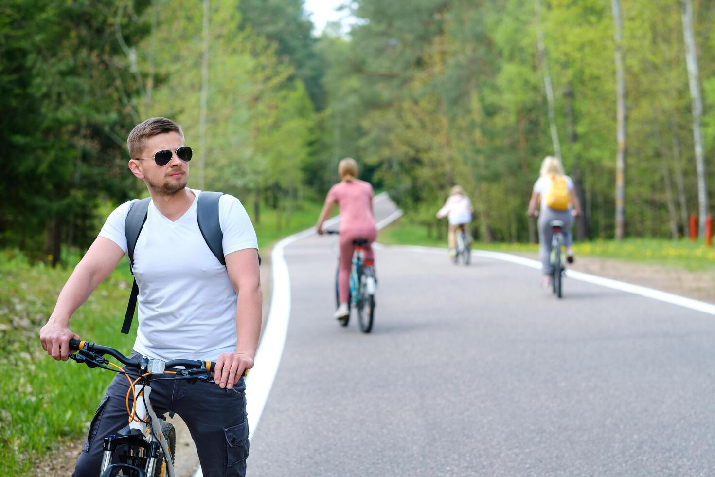 A group of cyclists with backpacks ride bicycles on a forest road enjoying nature photo