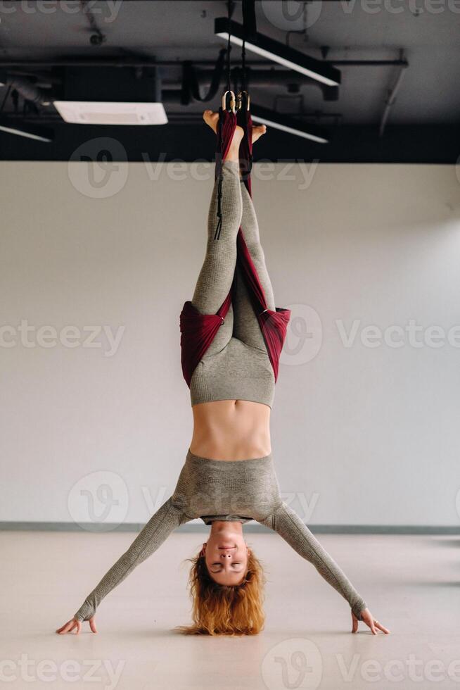 A woman hanging on a hanging hammock does yoga in the gym photo
