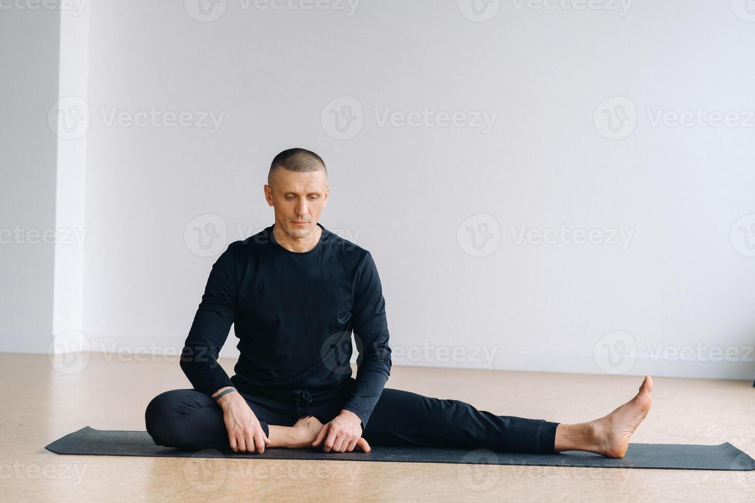 A man in sports clothes trains lying down, doing stretches in the gym. photo