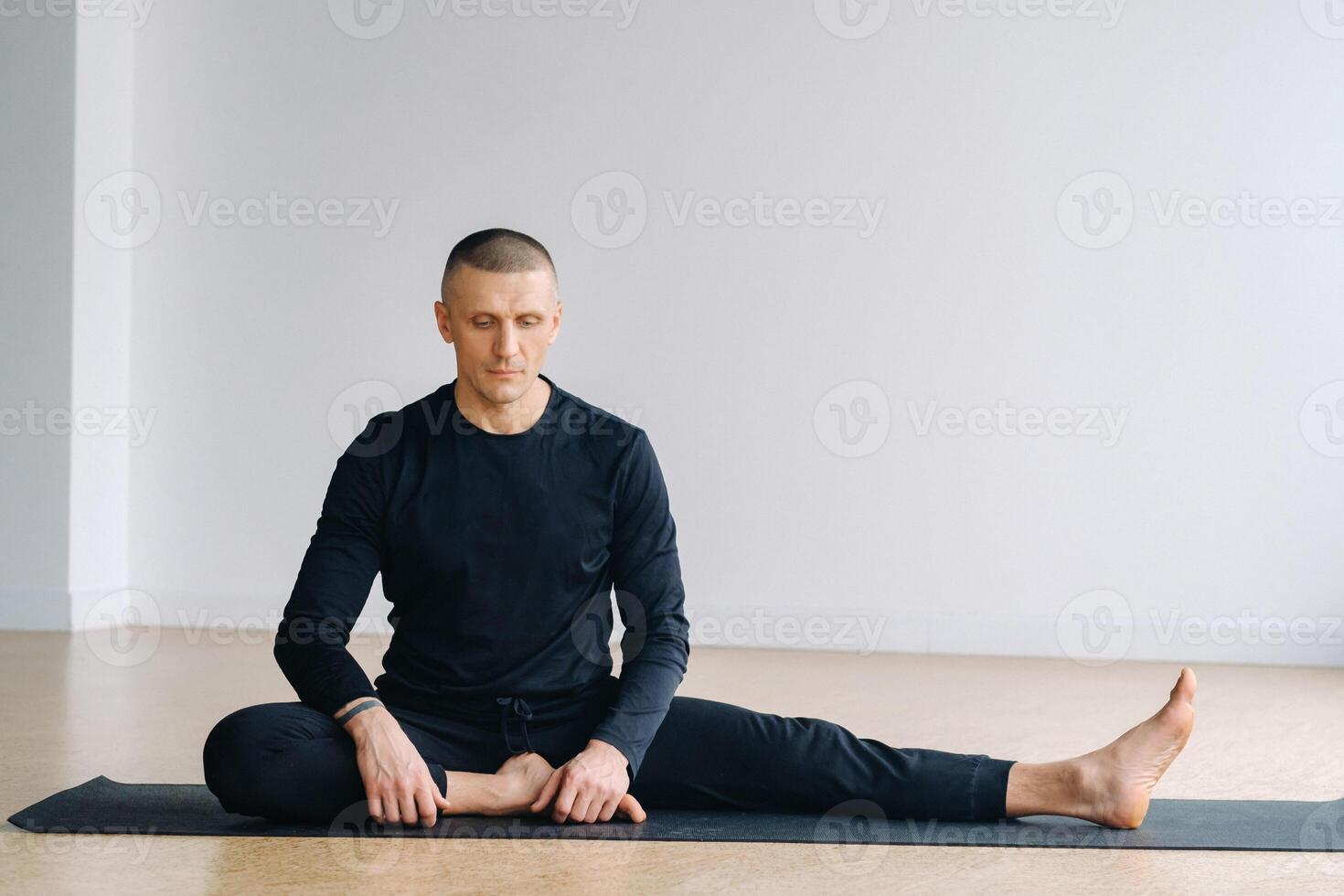 A man in sports clothes trains lying down, doing stretches in the gym. photo