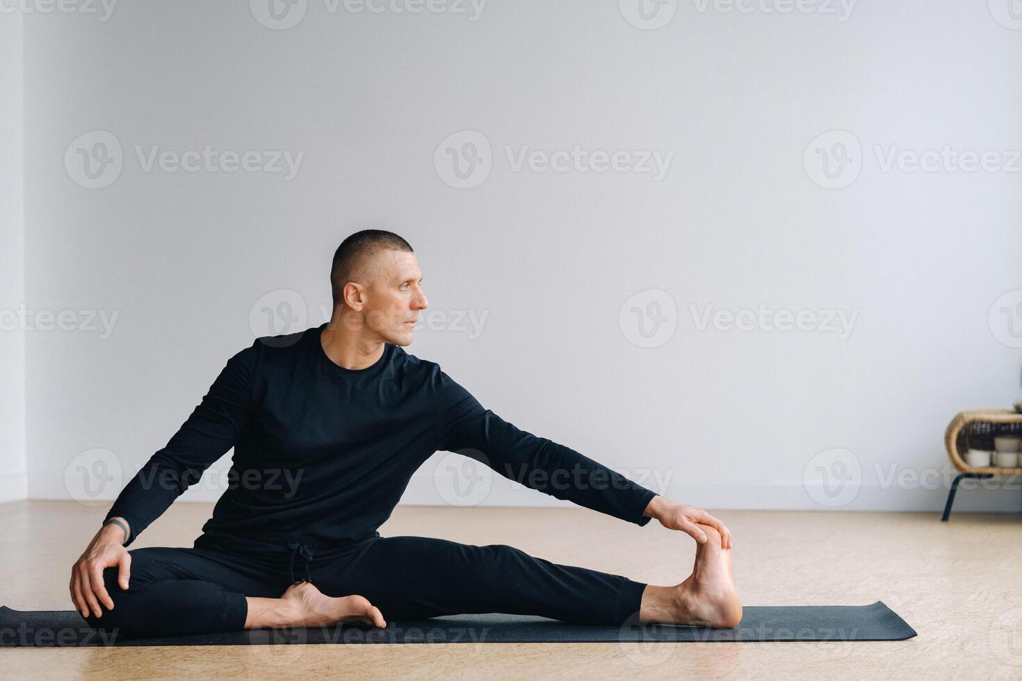 A man in sports clothes trains lying down, doing stretches in the gym. photo
