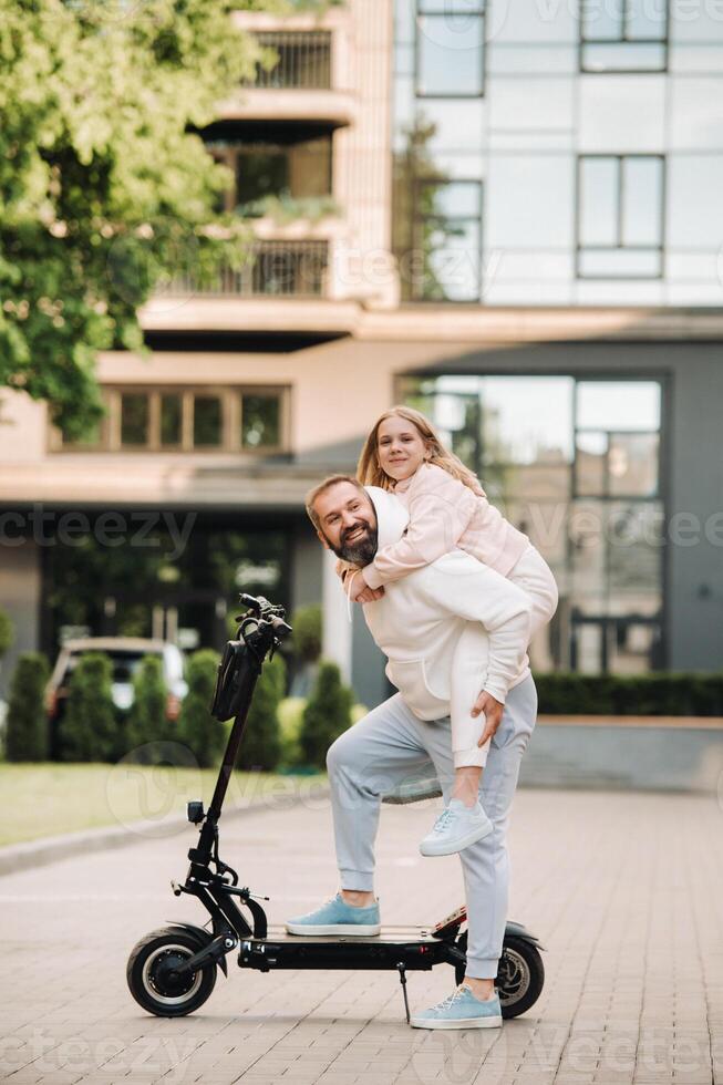 A family in white clothes stands in the city on electric scooters.Father and daughter on an electric scooter photo