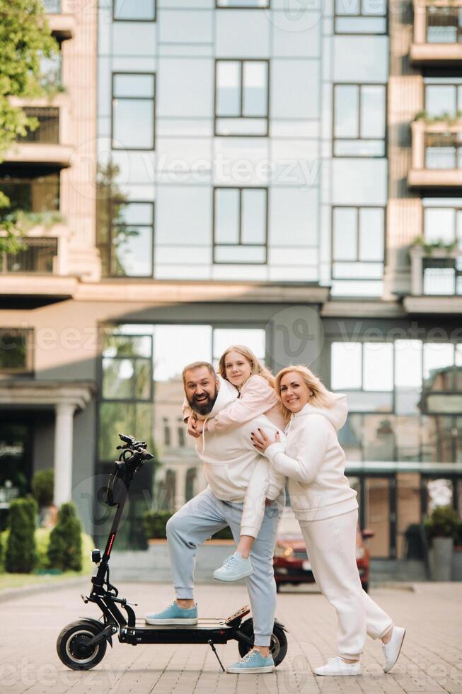 A family in white clothes stands in the city on electric scooters photo