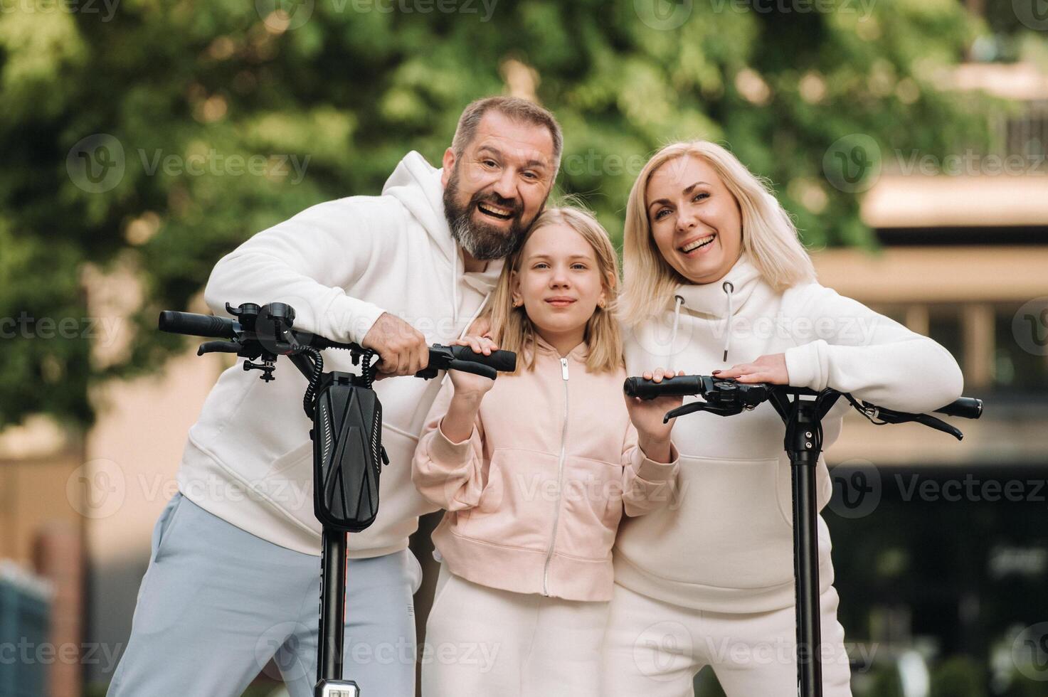 A family in white clothes stands in the city on electric scooters photo