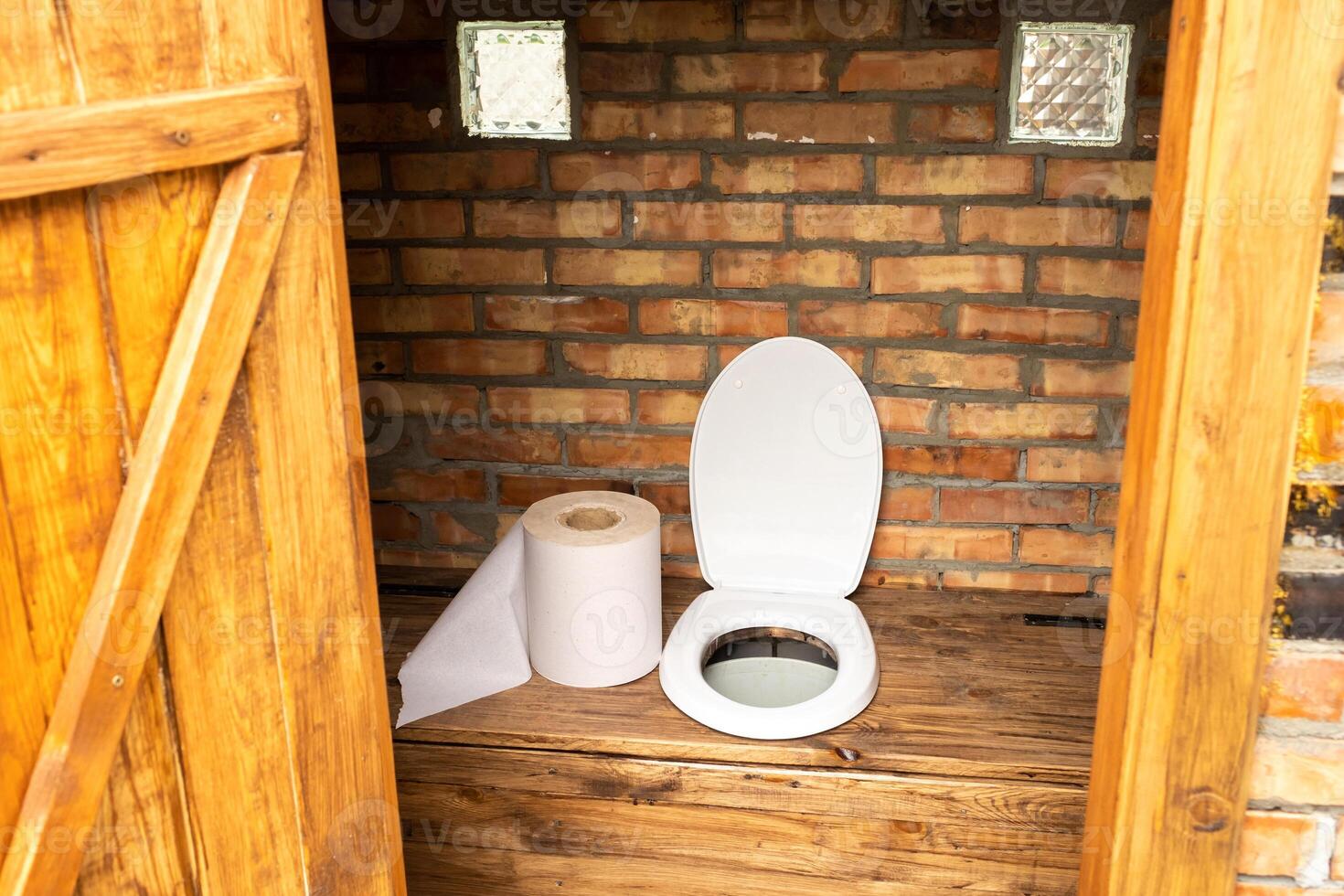 A simple village toilet with a huge roll of toilet paper.Large roll of toilet paper in the toilet photo