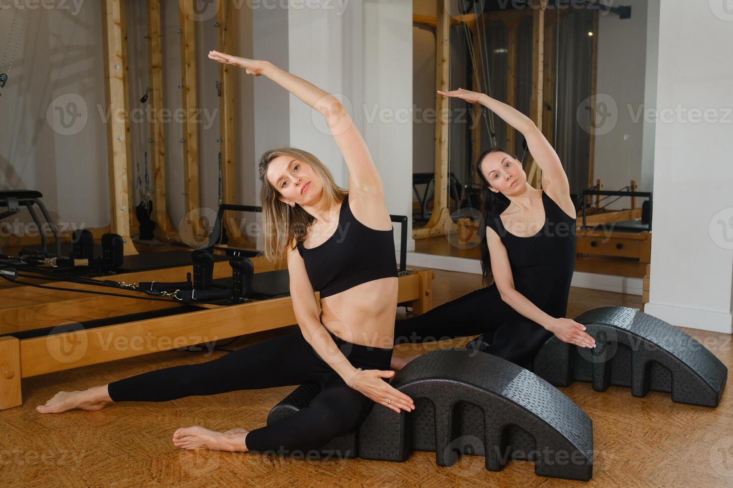Two women exercising on the Pilates Arch machine at the gym. photo
