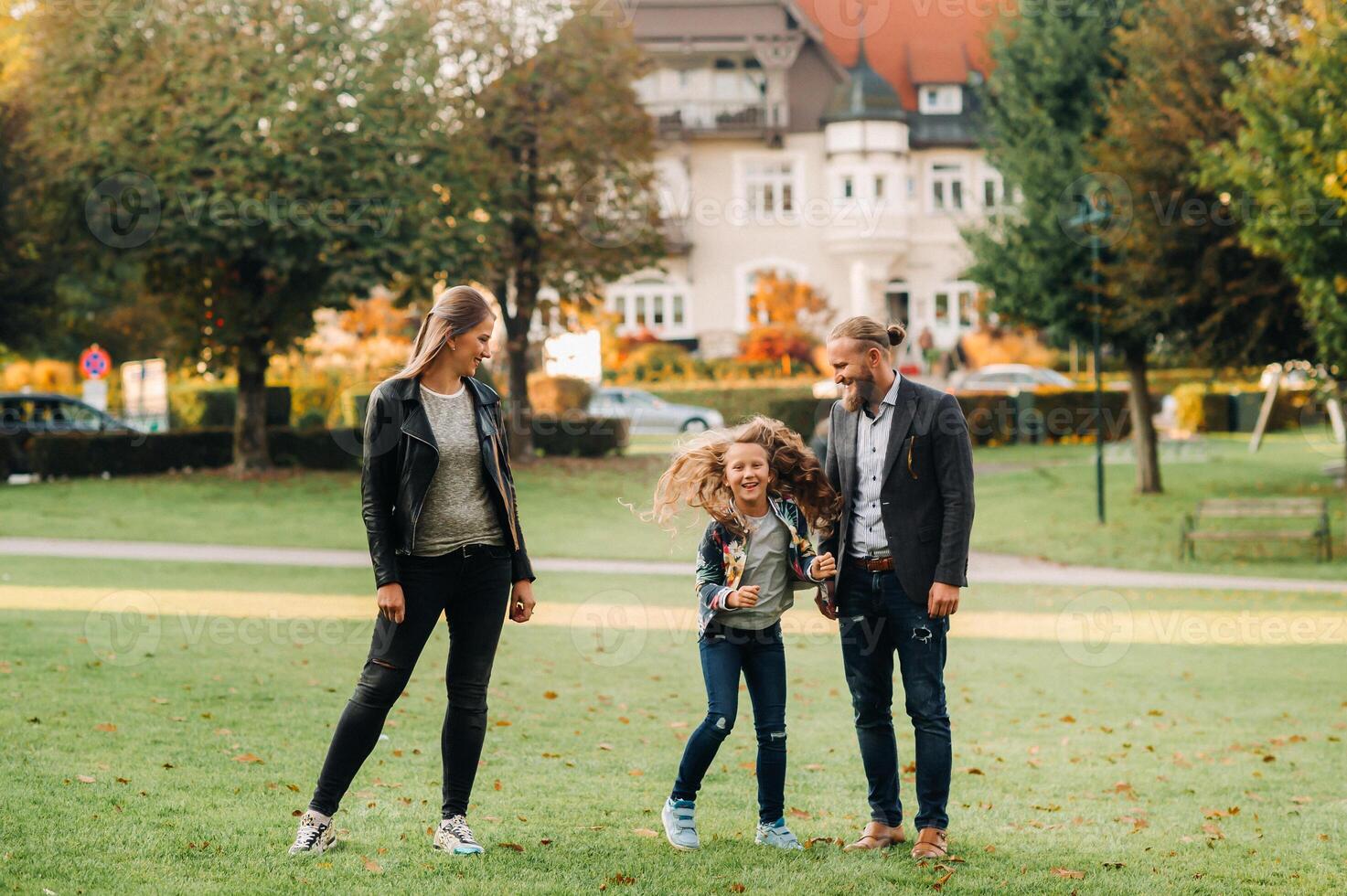A happy family of three runs through the grass in Austria's old town.A family walks through a small town in Austria.Europe.Velden am werten Zee photo