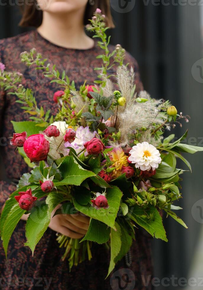 A large bouquet of mixed flowers in the hands of a woman. The work of a florist in a flower shop photo