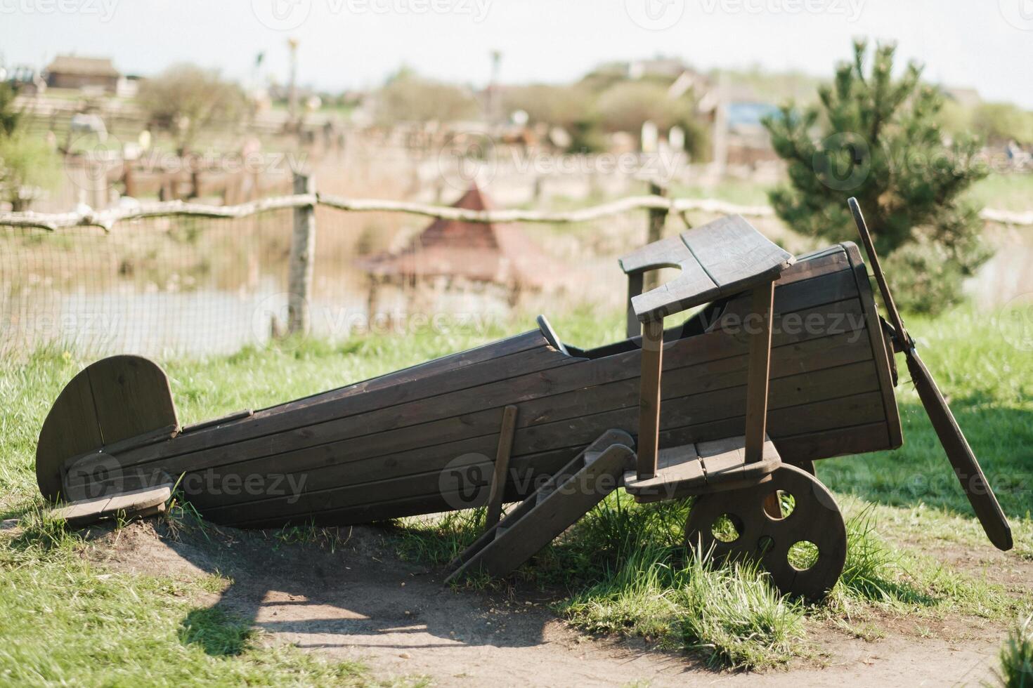 A wooden model of an airplane standing on the street in summer photo
