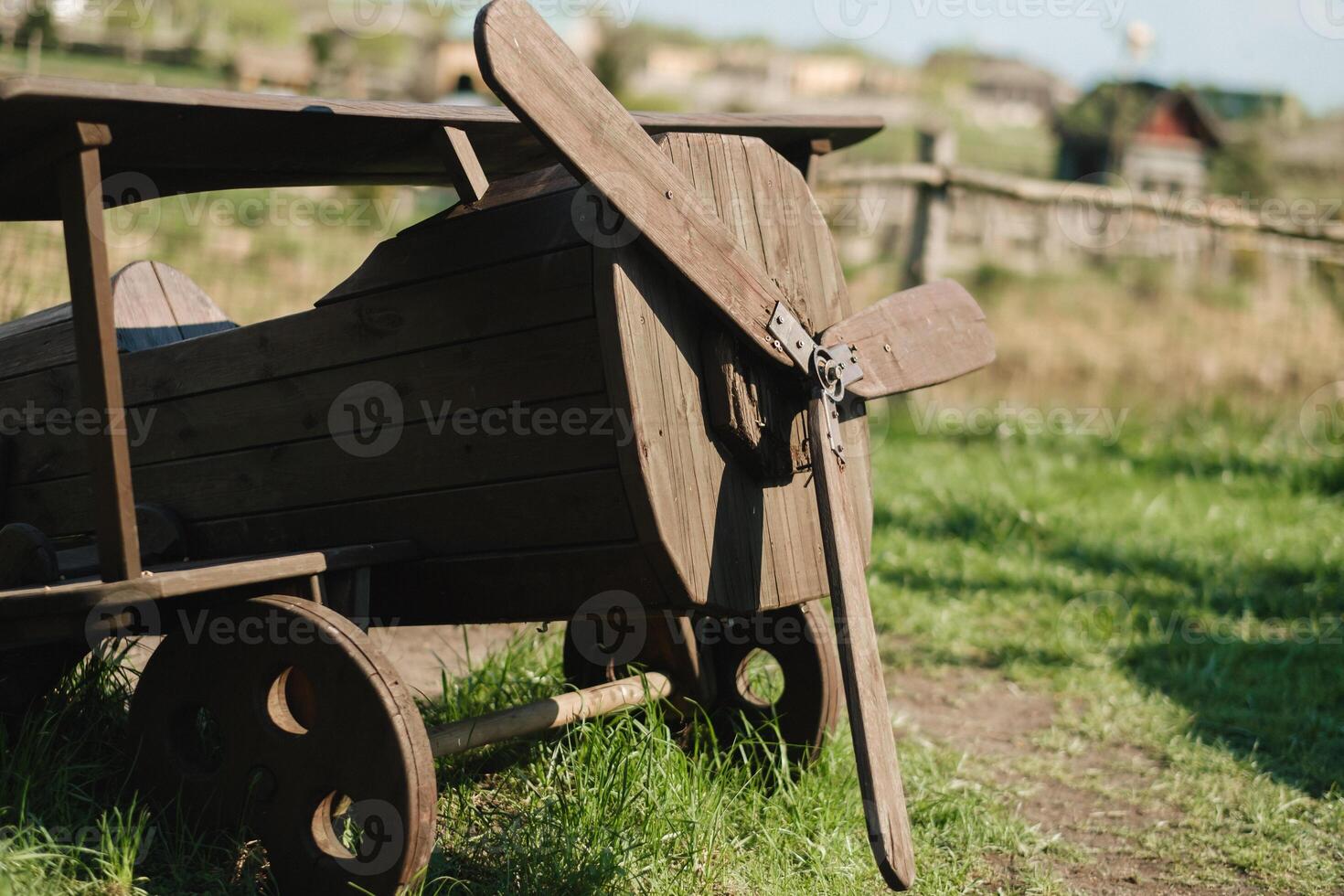 A wooden model of an airplane standing on the street in summer photo