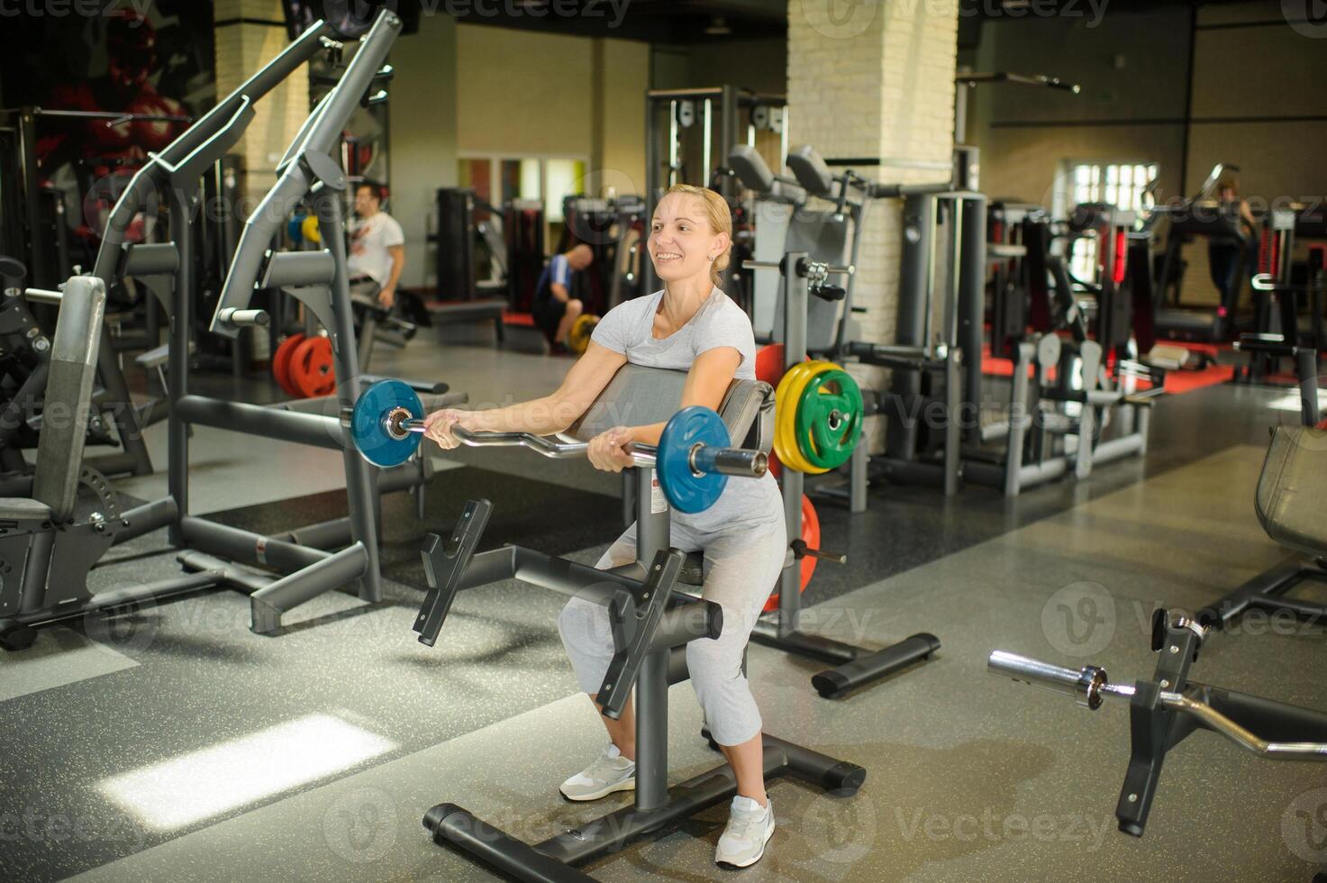 Woman training biceps with a barbell in the gym. Strength training with heavy equipment photo