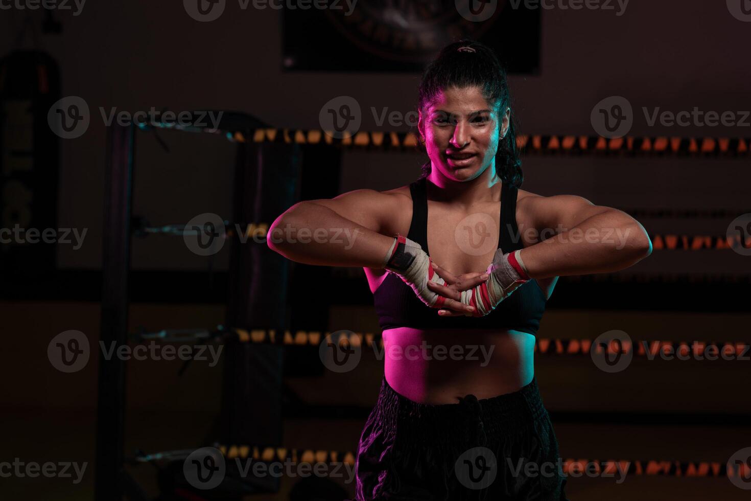 female Latina boxer with her hands bandaged working out at a training session at a gym throwing a punch photo