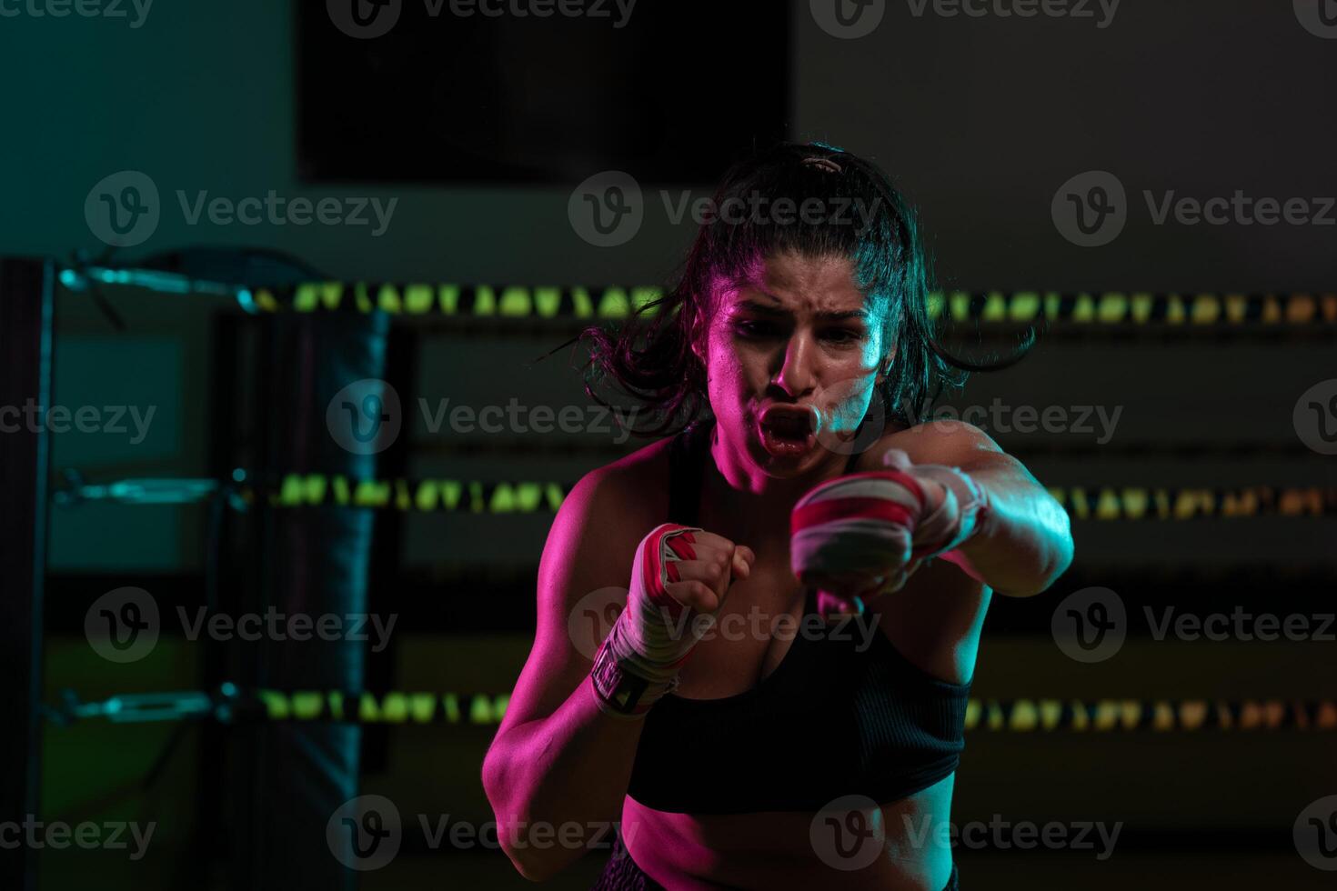 female Latina boxer with her hands bandaged working out at a training session at a gym throwing a punch photo