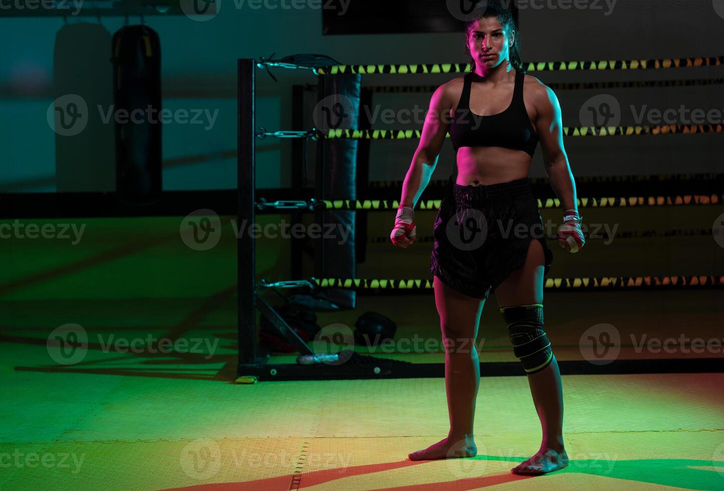 Portrait young Latina boxer woman wrapping hand with sport bandage on black background photo
