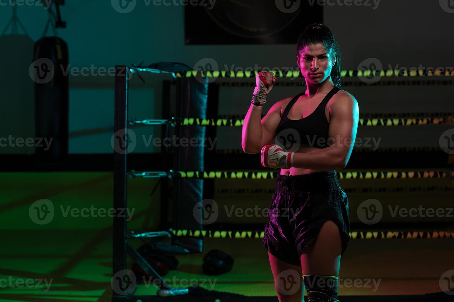 Portrait young Latina boxer woman wrapping hand with sport bandage on black background photo