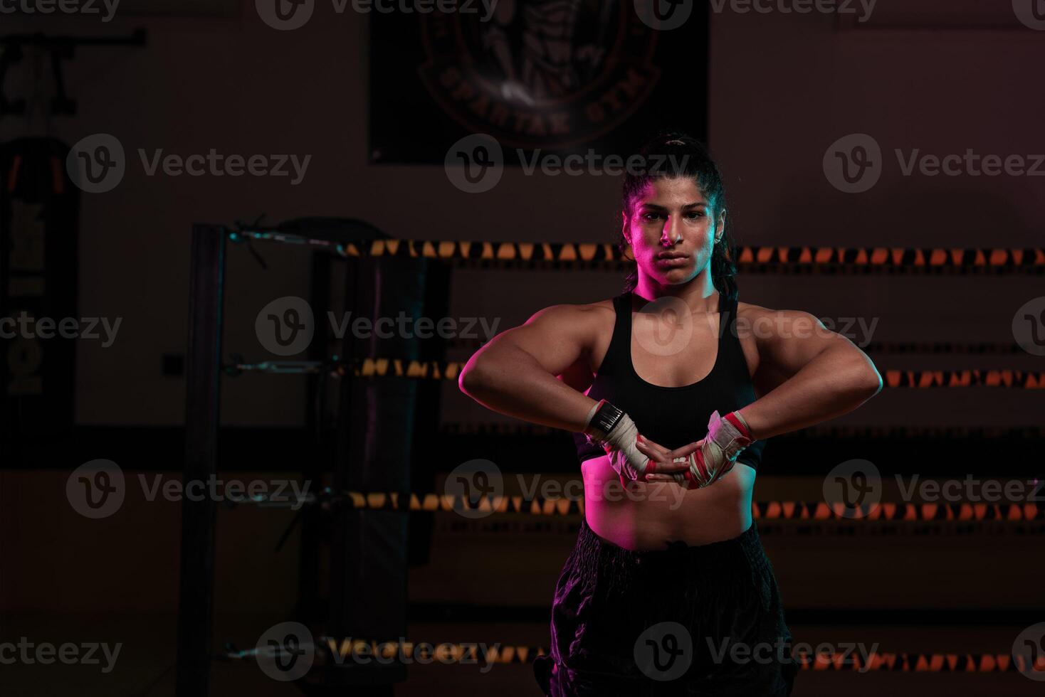 female Latina boxer with her hands bandaged working out at a training session at a gym throwing a punch photo