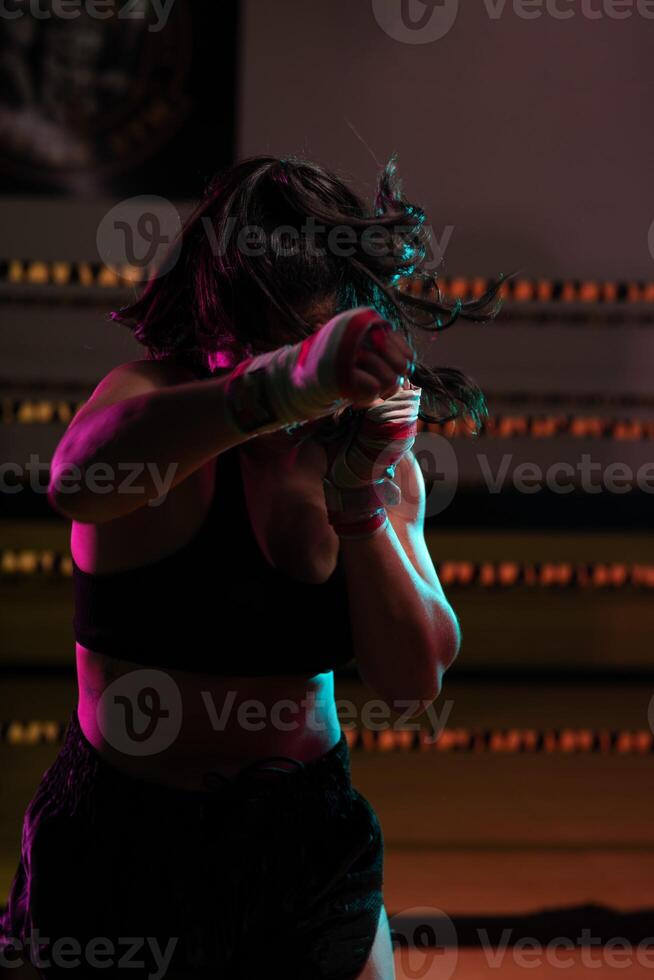 female Latina boxer with her hands bandaged working out at a training session at a gym throwing a punch photo