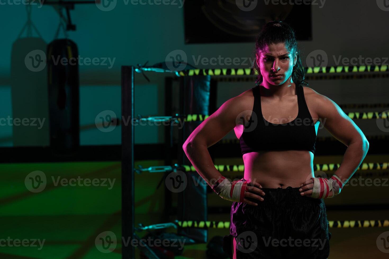 Portrait young Latina boxer woman wrapping hand with sport bandage on black background photo