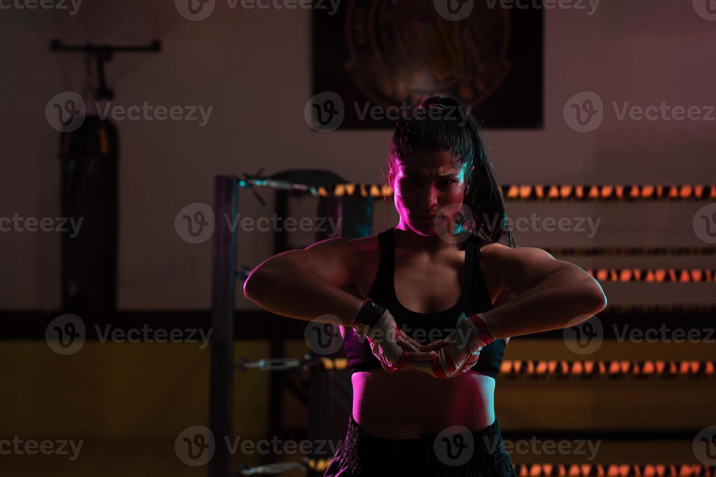 female Latina boxer with her hands bandaged working out at a training session at a gym throwing a punch photo
