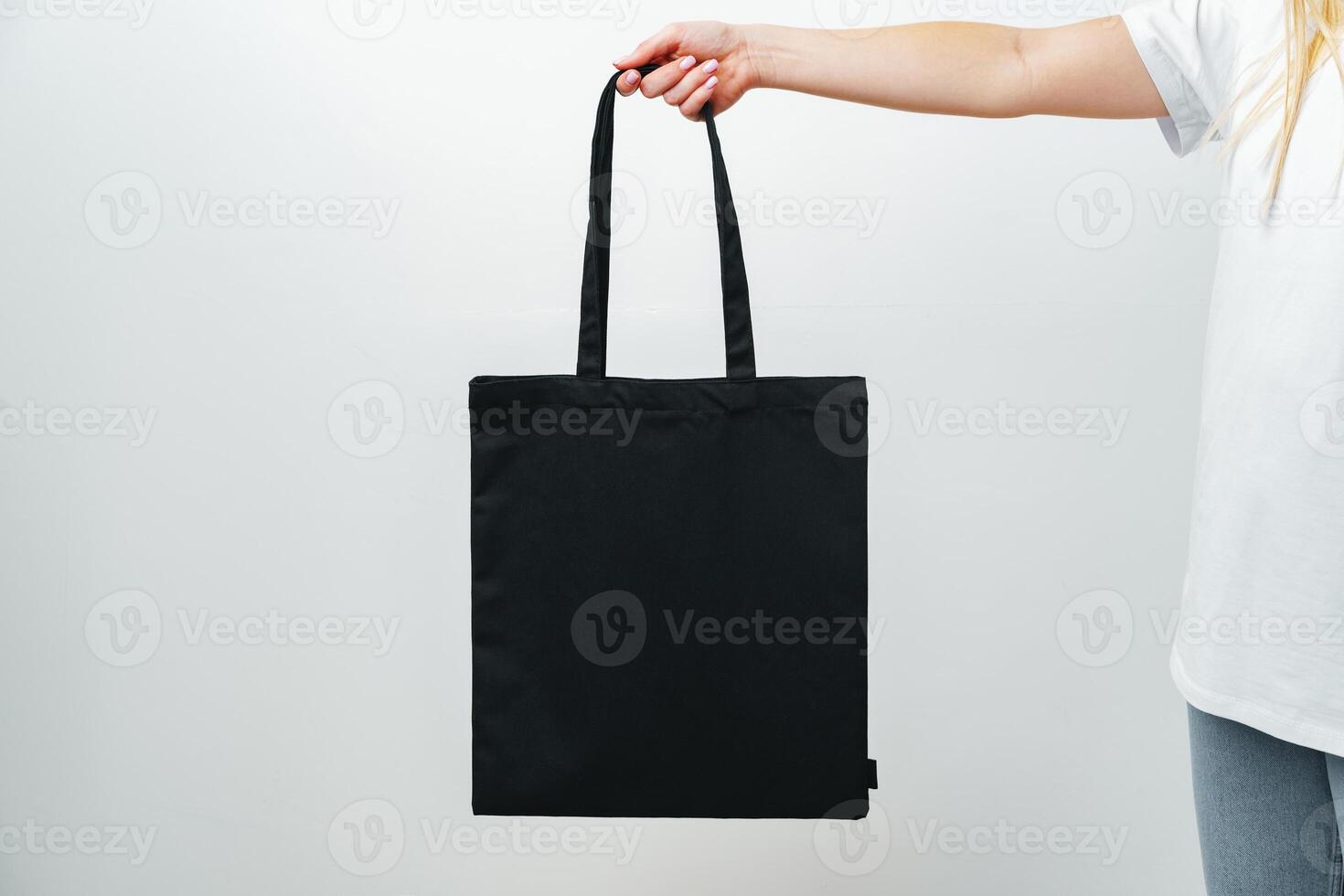 Female hand holding eco or reusable shopping bag against white background photo