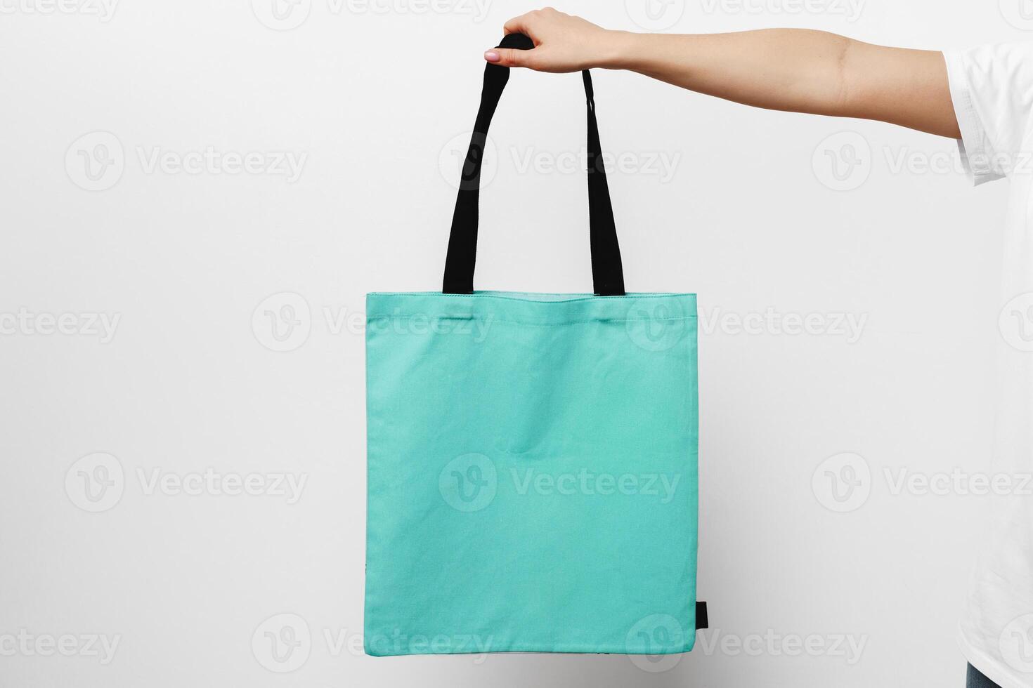 Female hand holding eco or reusable shopping bag against white background photo